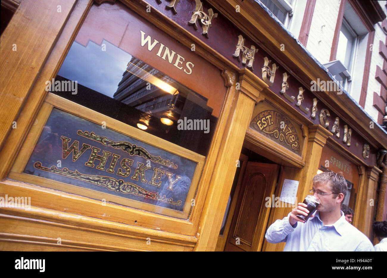 Uomo di bere birra di fronte al Mulligan's Pub, Dublino, Irlanda Foto Stock