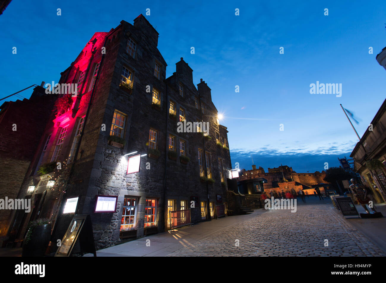 Città di Edimburgo in Scozia. Vista notturna di Cannonball casa in cima al Royal Mile, con il Castello di Edimburgo in background. Foto Stock