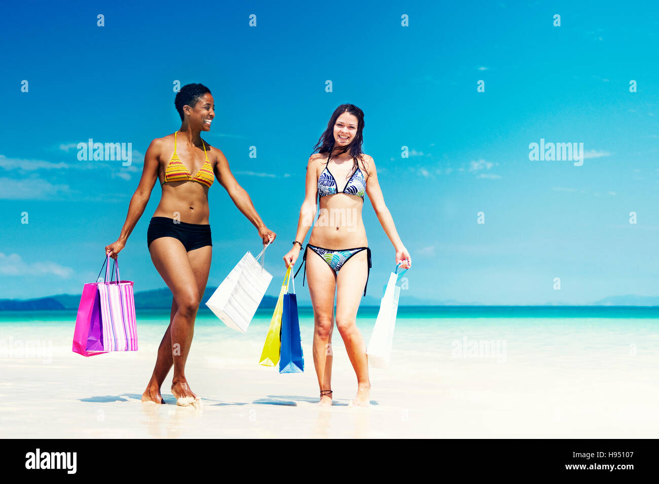 Le donne con le borse della spesa su una spiaggia tropicale Concept Foto Stock