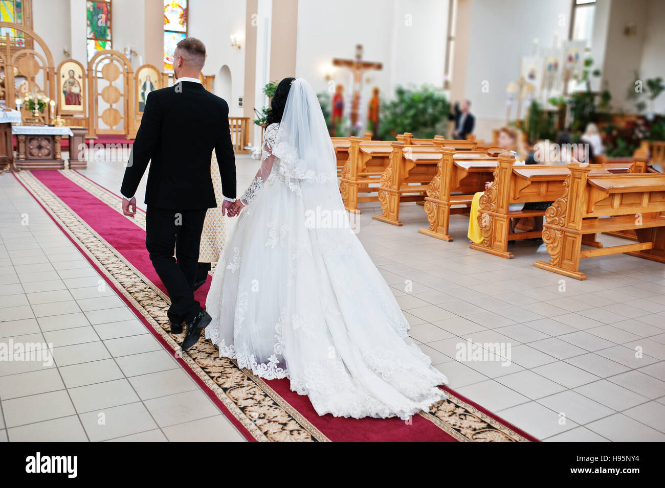 Coppie in viaggio di nozze di andare alla mensa del Signore altare sulla cerimonia di matrimonio in chiesa. Foto Stock
