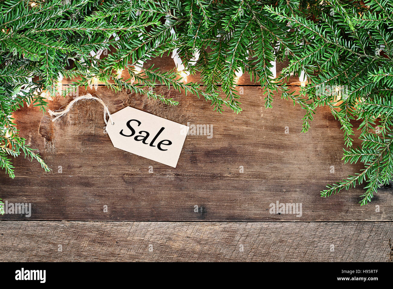 Albero di natale rami di pino, vendite tag e luci decorative su un sfondo rustico di legno del granaio. Immagine ripresa dalla testa. Foto Stock