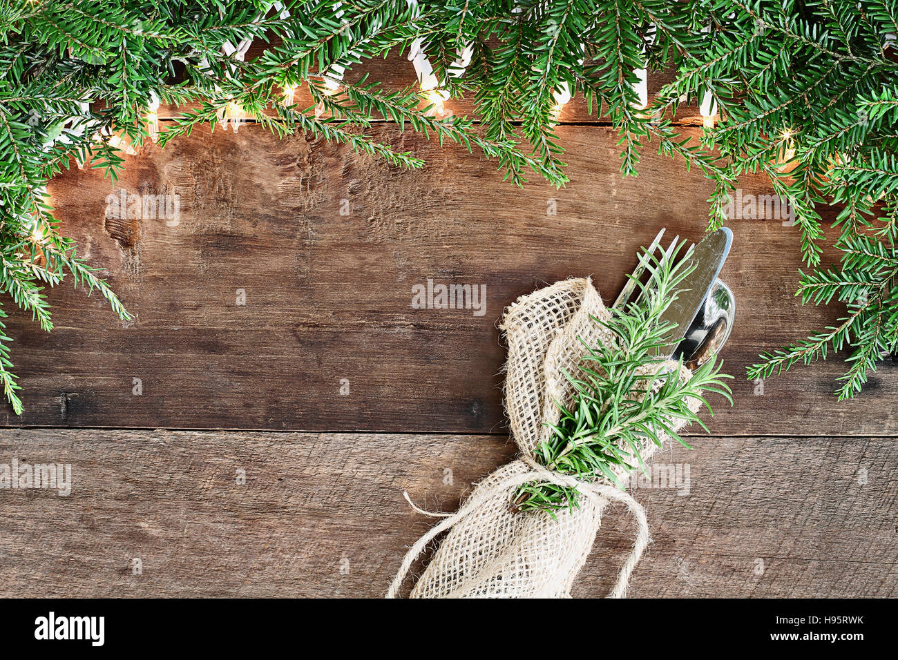 Albero di natale di rami di pino e luci decorative con posate su un sfondo rustico di legno del granaio. Immagine ripresa dalla testa. Foto Stock