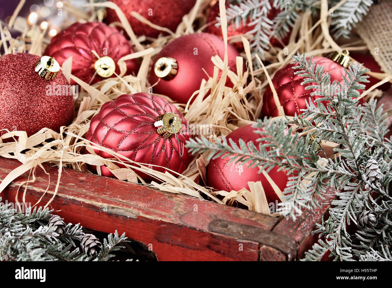 Vetro Ornamenti natale pranzo in un antico scatola di legno con coperte di neve rami di pino che li circondano. Foto Stock