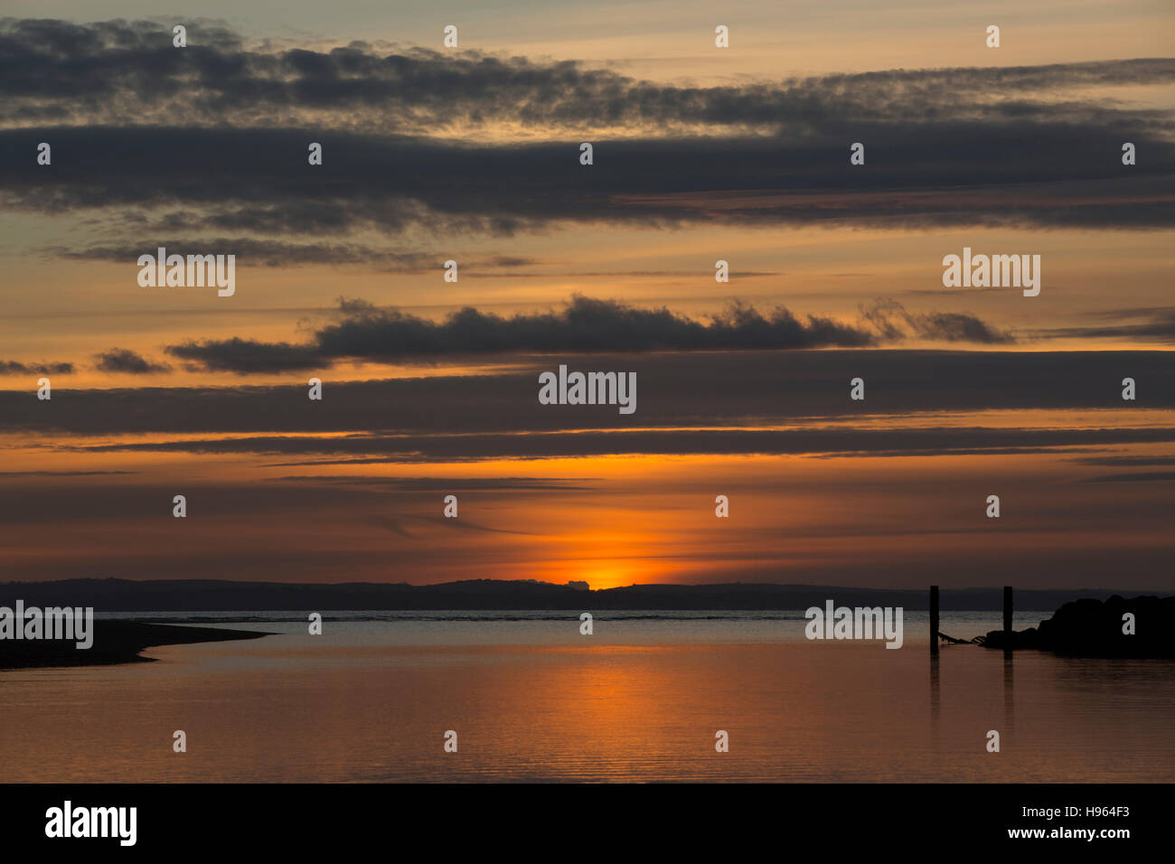 Spiaggia di segno del marcatore in mare contro una vivida del tramonto. Calma di mare e di terra e oltre. Cielo colorato off Hayling Island Hampshire Foto Stock