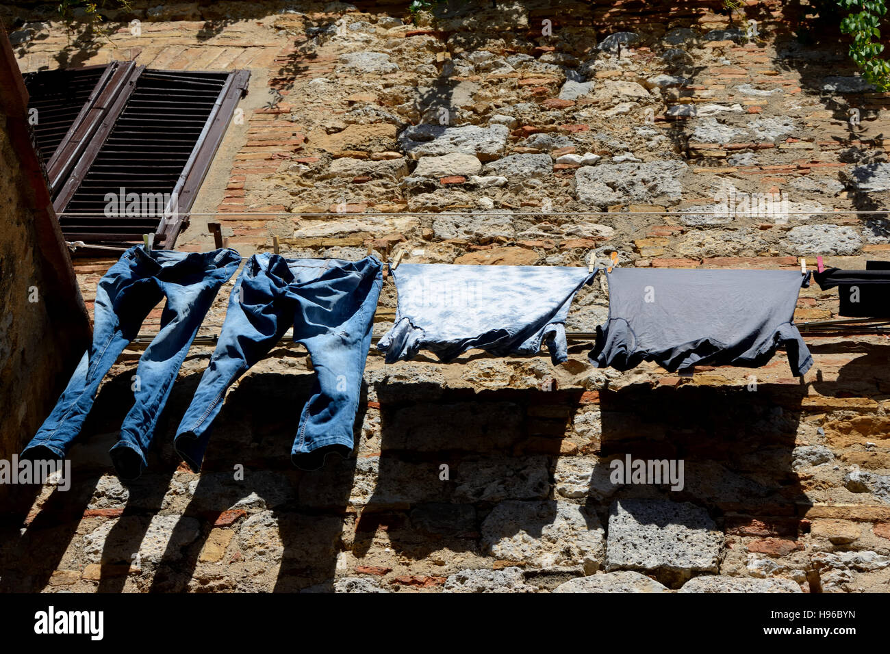 Vestiti appesi a mattoni vecchi e muro di pietra Foto Stock