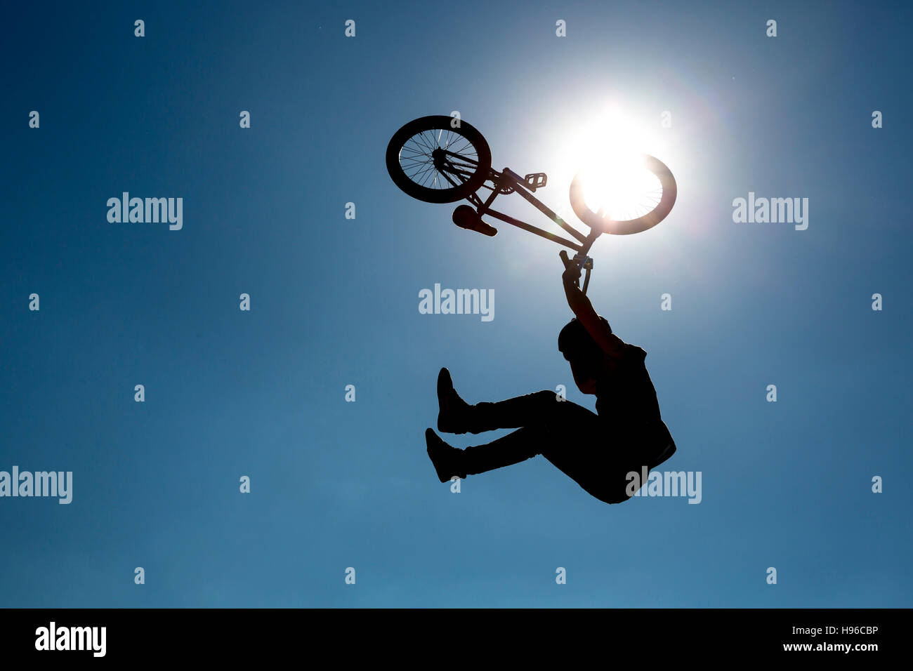 Silhouette di un ciclista jumping contro il cielo blu e il sole. Foto Stock
