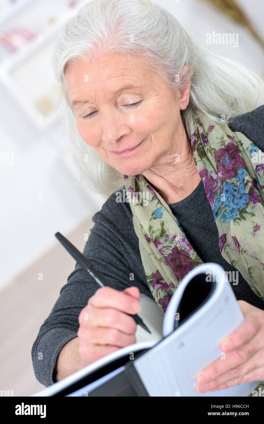 Vecchia donna con un cruciverba in salotto Foto Stock