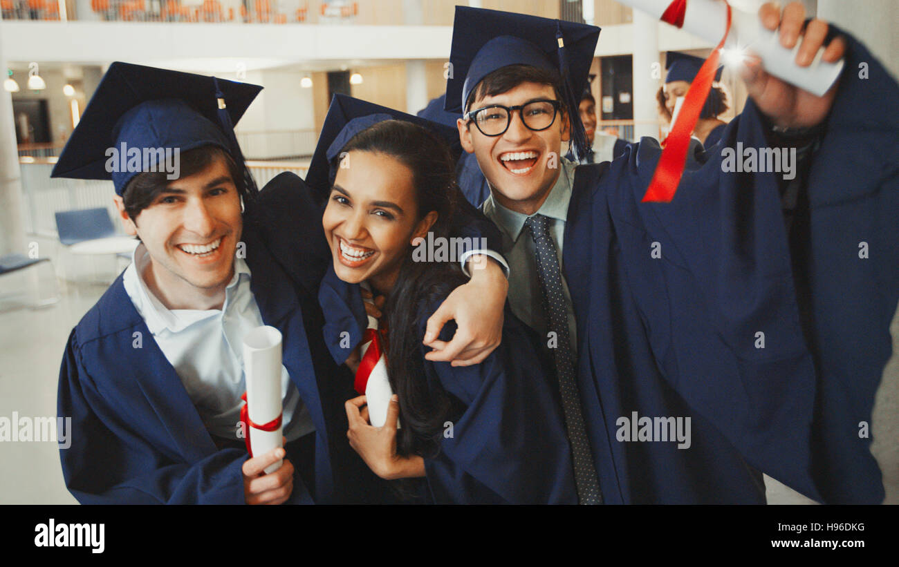Ritratto entusiastico laureati nel cappuccio e camice con diplomi Foto Stock