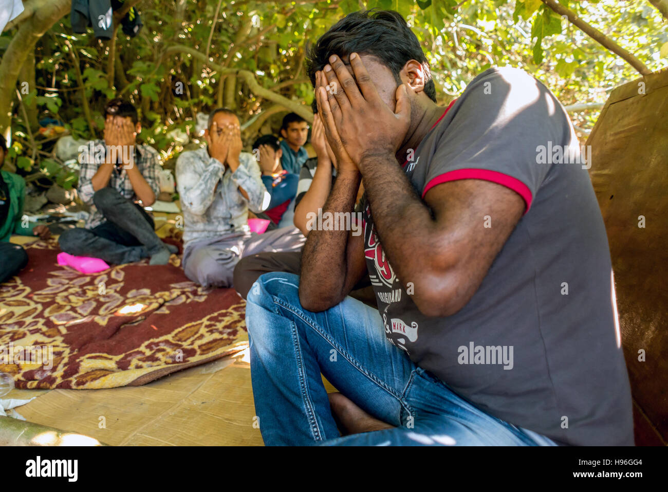 Profughi pakistani nascondono i loro volti come si nascondono in un bosco vicino a Bodrum, Turchia, in attesa di un passaggio per la Grecia e l'Europa. Foto Stock