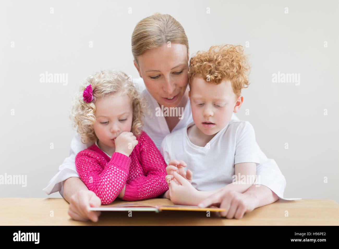 Madre libro di lettura al figlio (8-9) e la figlia (4-5) Foto Stock