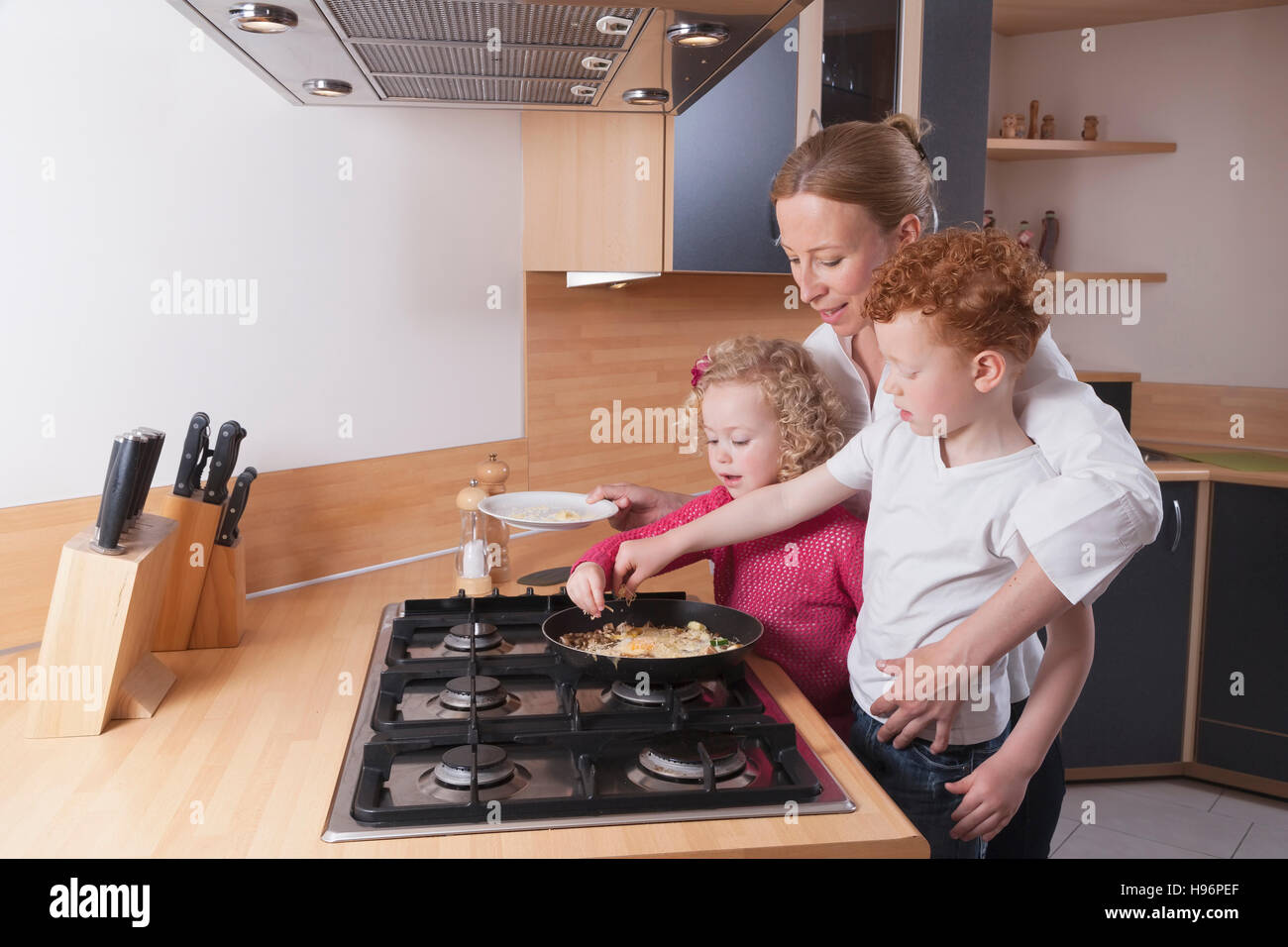 Figlia della madre (4-5) e figlio (8-9) preparare le uova strapazzate insieme Foto Stock