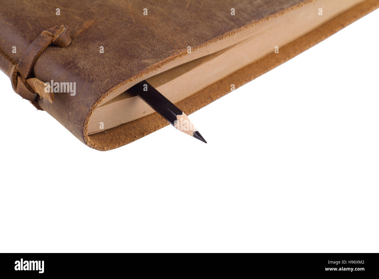 In prossimità di una matita nera tra le pagine di un notebook con cuoio marrone copre isolato su bianco Foto Stock