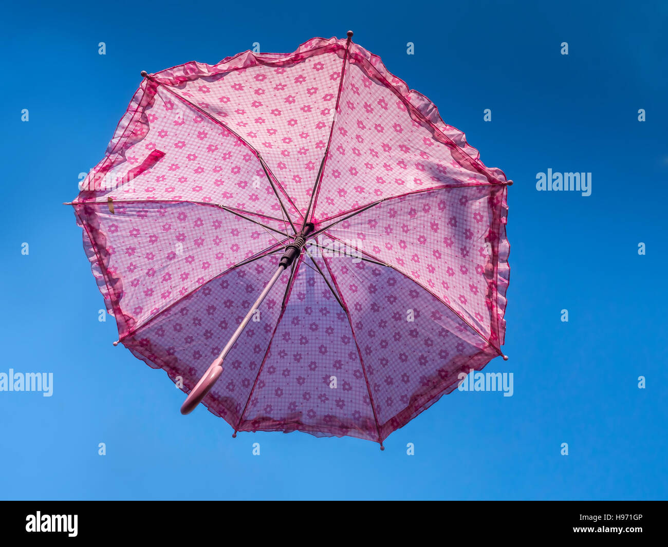 Ombrello rosa rising alta nel cielo blu Foto Stock