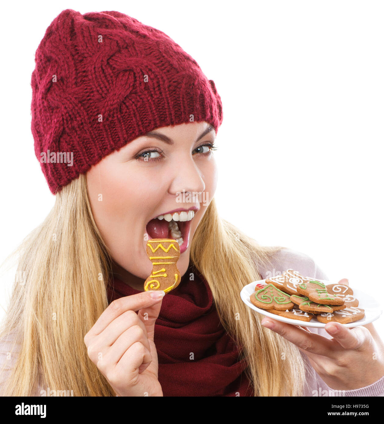 Sorridenti donna che indossa cappello di lana e scialle e azienda gingerbreads o cookie di festosa, tempo di Natale, sfondo bianco Foto Stock