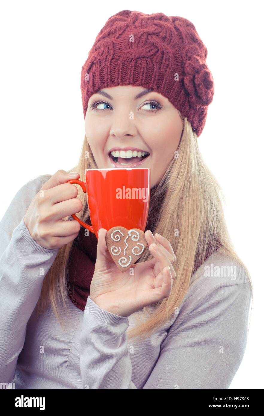 Foto d'epoca, donna sorridente indossando cappello di lana e scialle, tenendo gingerbread o cookie di festosa e rosso tazza di tè caldo, sfondo bianco Foto Stock