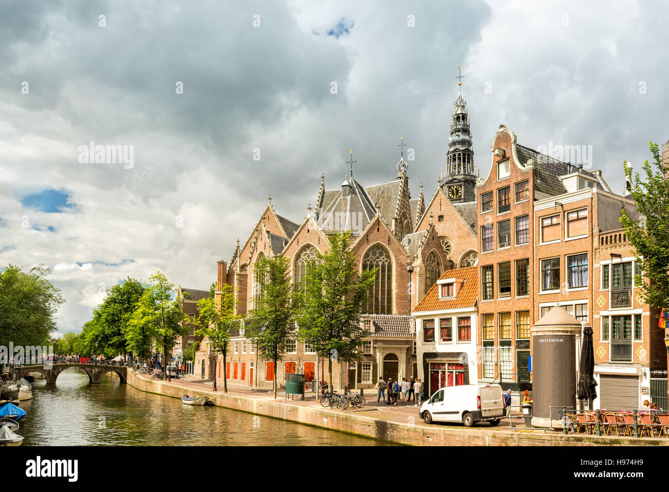 Amsterdam Quartiere a Luci Rosse di canal con la vecchia chiesa (aka De Oude Kerk) tra le tipiche case olandesi, su una soleggiata mattina d'estate Foto Stock