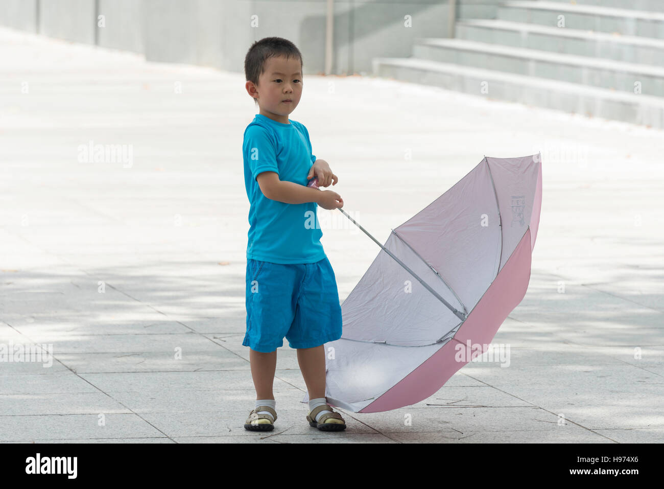 Piccolo ragazzo asiatico holding ombrello, Imperatrice Luogo, quartiere Civico, isola di Singapore, Singapore Foto Stock