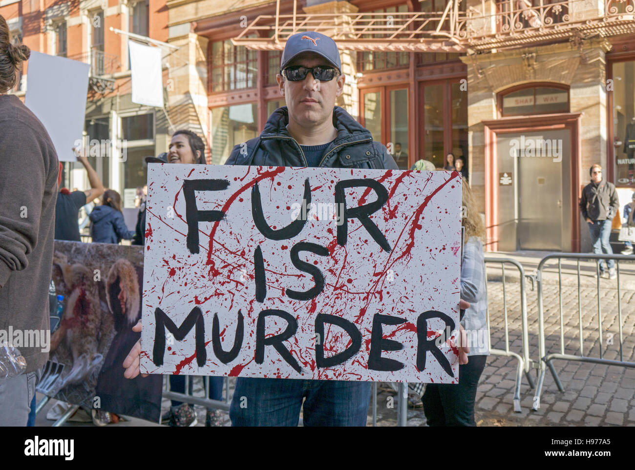 Un dimostratore con una pelliccia è segno di omicidio protestando il trattamento degli animali al di fuori del Canada Goose store a Soho, New York. Foto Stock