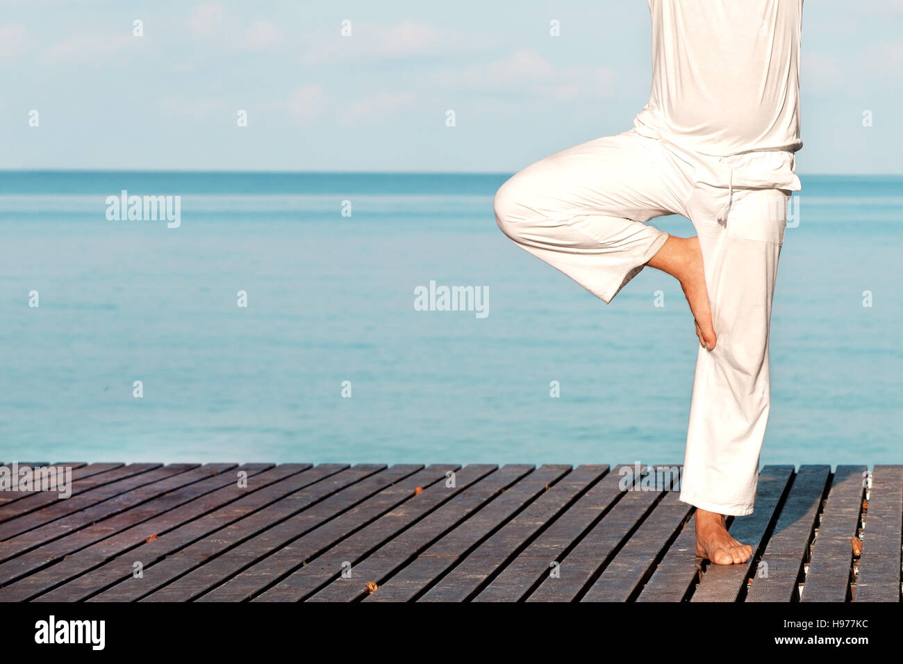 Uomo caucasico in bianche vesti la meditazione yoga sul molo in legno Foto Stock