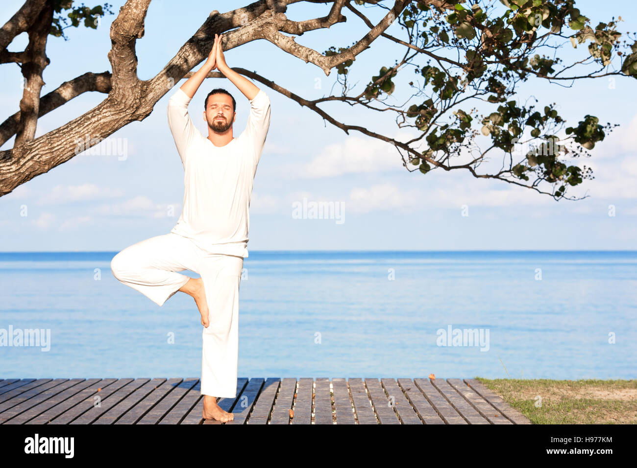 Uomo caucasico in bianche vesti la meditazione yoga sul molo in legno Foto Stock