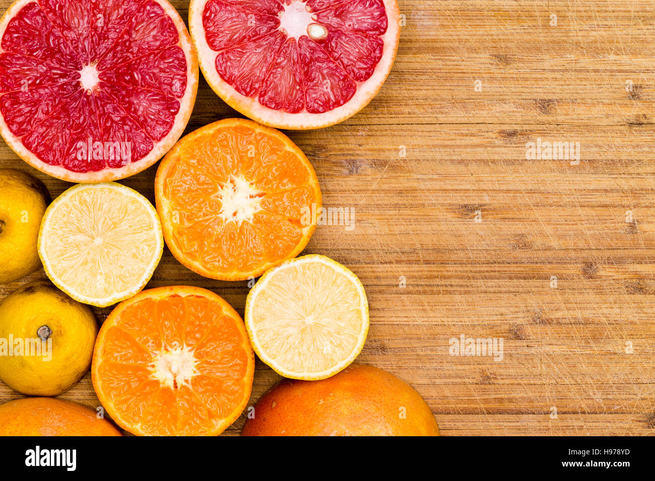 Angolo alto ancora vista la vita di fettine di ripe rosso rubino Pompelmi e pomeli, arance e limoni disposti su rustiche tagliere di legno con spazio di copia Foto Stock