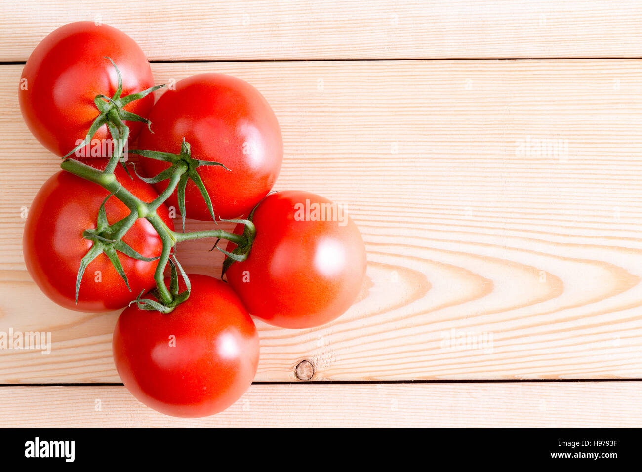 Cinque profonde maturi rossi pomodori medi incompiuta su tavole di legno. Include lo spazio di copia. Foto Stock