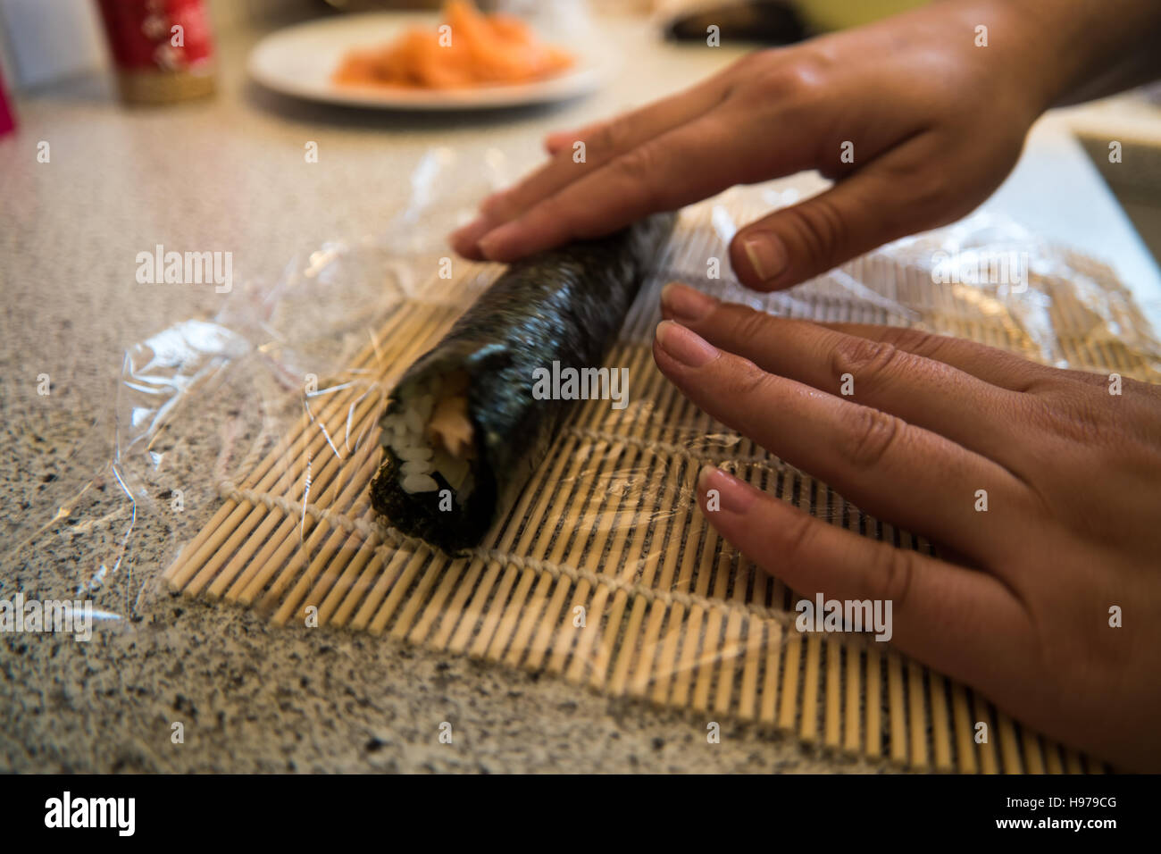 Mettere il sushi insieme utilizzando alghe, salmone, di riso e di cetriolo Foto Stock
