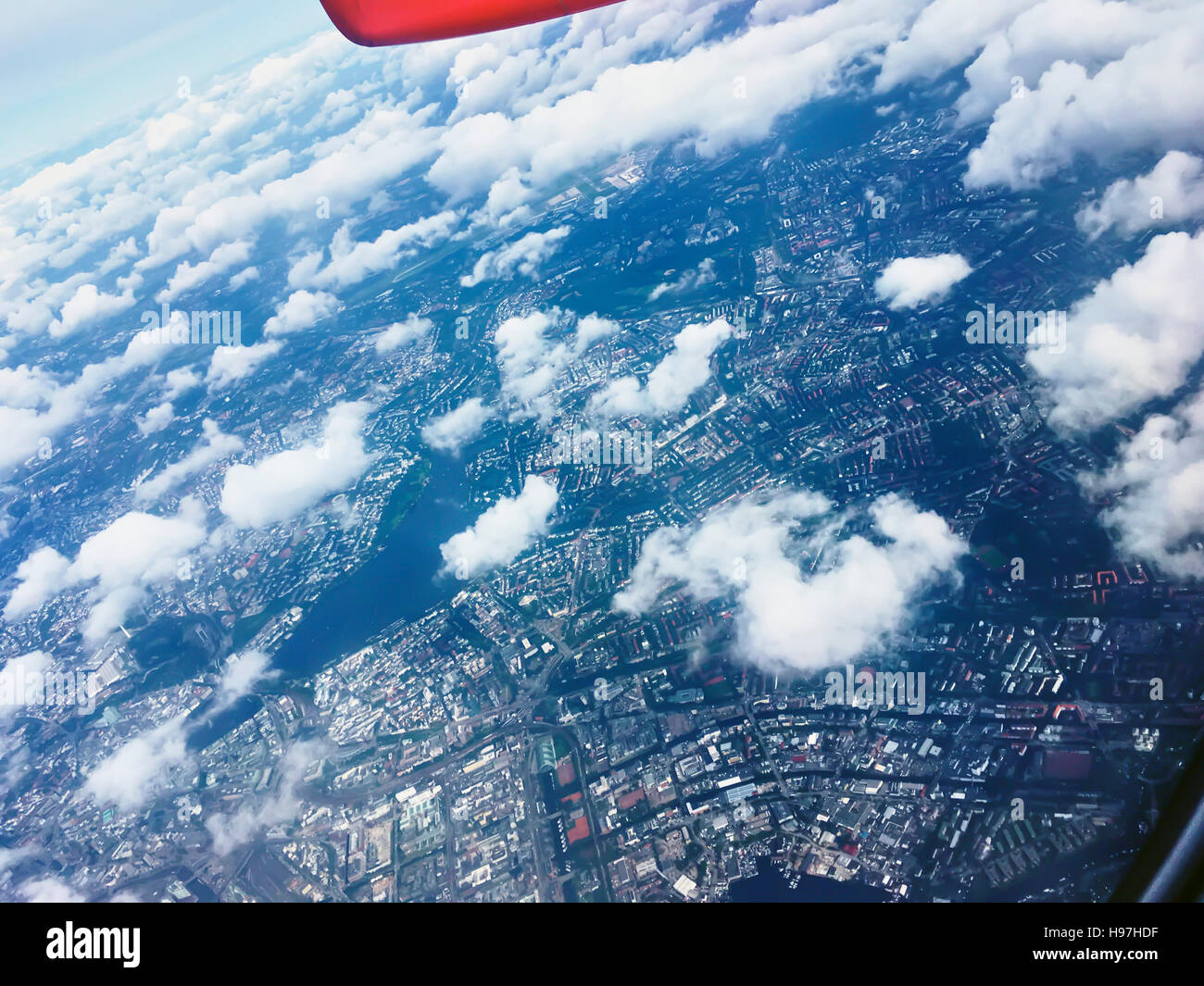 Volo sopra white cumulus nubi in un aereo con il wingtip e sentiero di vapori visibili in una soleggiata cielo blu in un concetto di trasporto Foto Stock