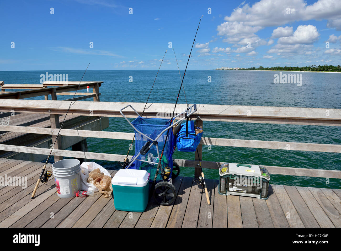 Pesca, aste, bobine appoggiata contro la ringhiera di protezione sul lato del molo Foto Stock