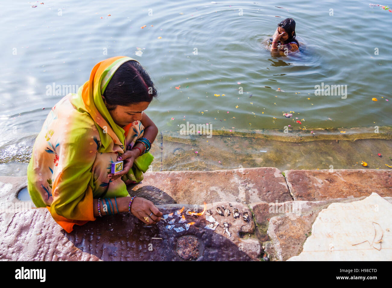 Donne accendendo candele per la puja e balneazione nel fiume Gange, Varanasi, India Foto Stock