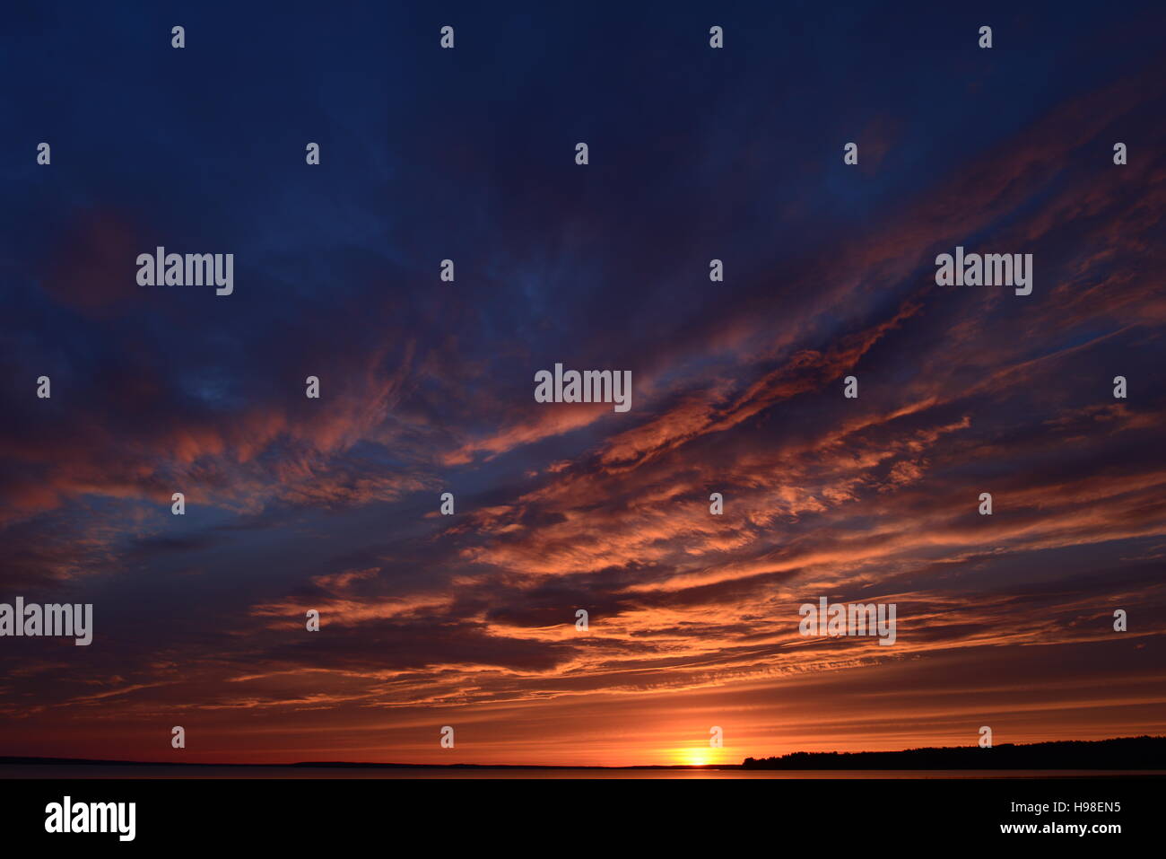 Blu cielo nuvoloso alla luce del tramonto sul lago Foto Stock