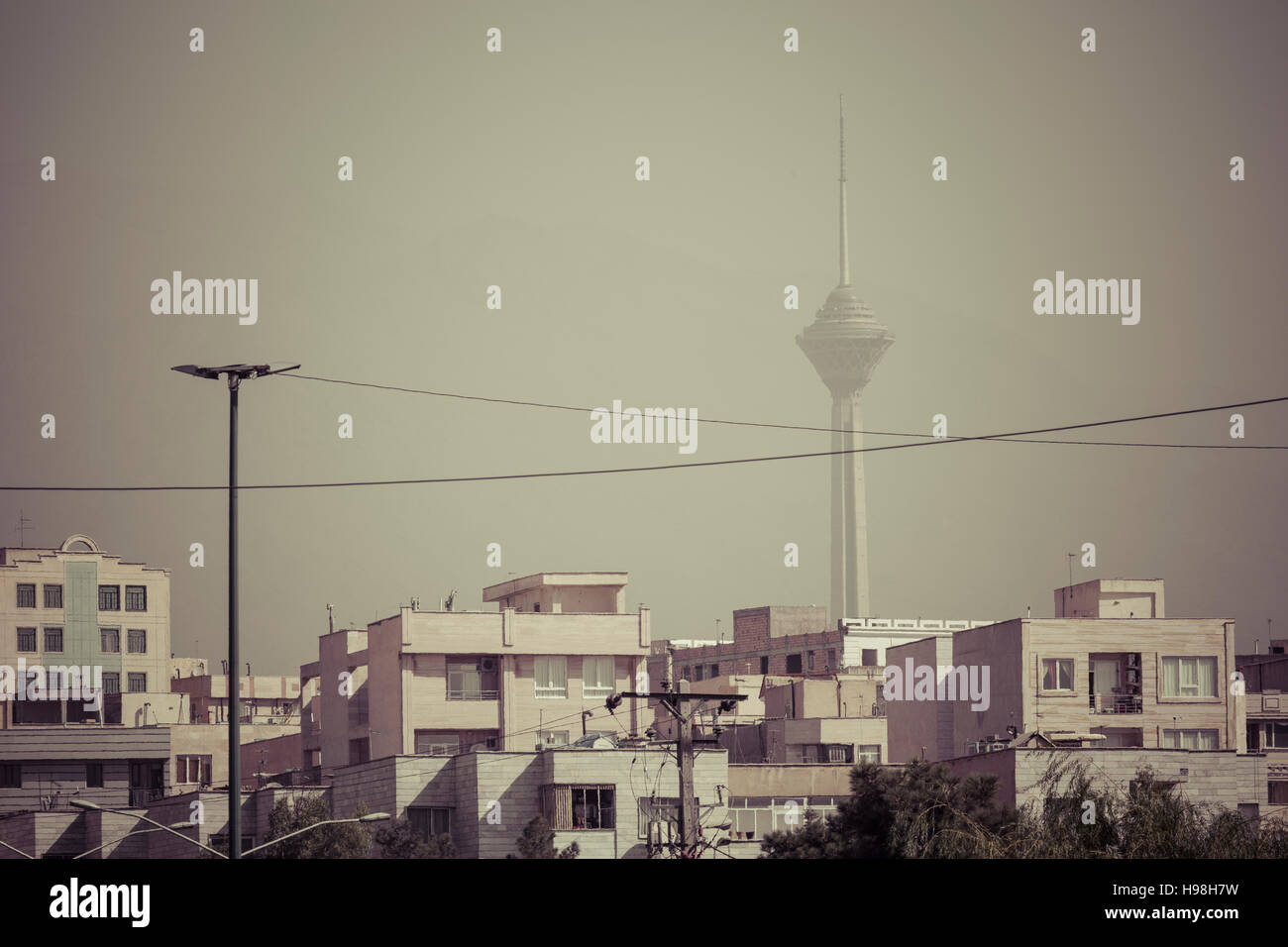 TEHERAN, IRAN - Ottobre 03, 2016: edifici residenziali a fronte di Milad Tower in aria contaminata skyline di Tehran illuminato con tramonto dorato. Foto Stock