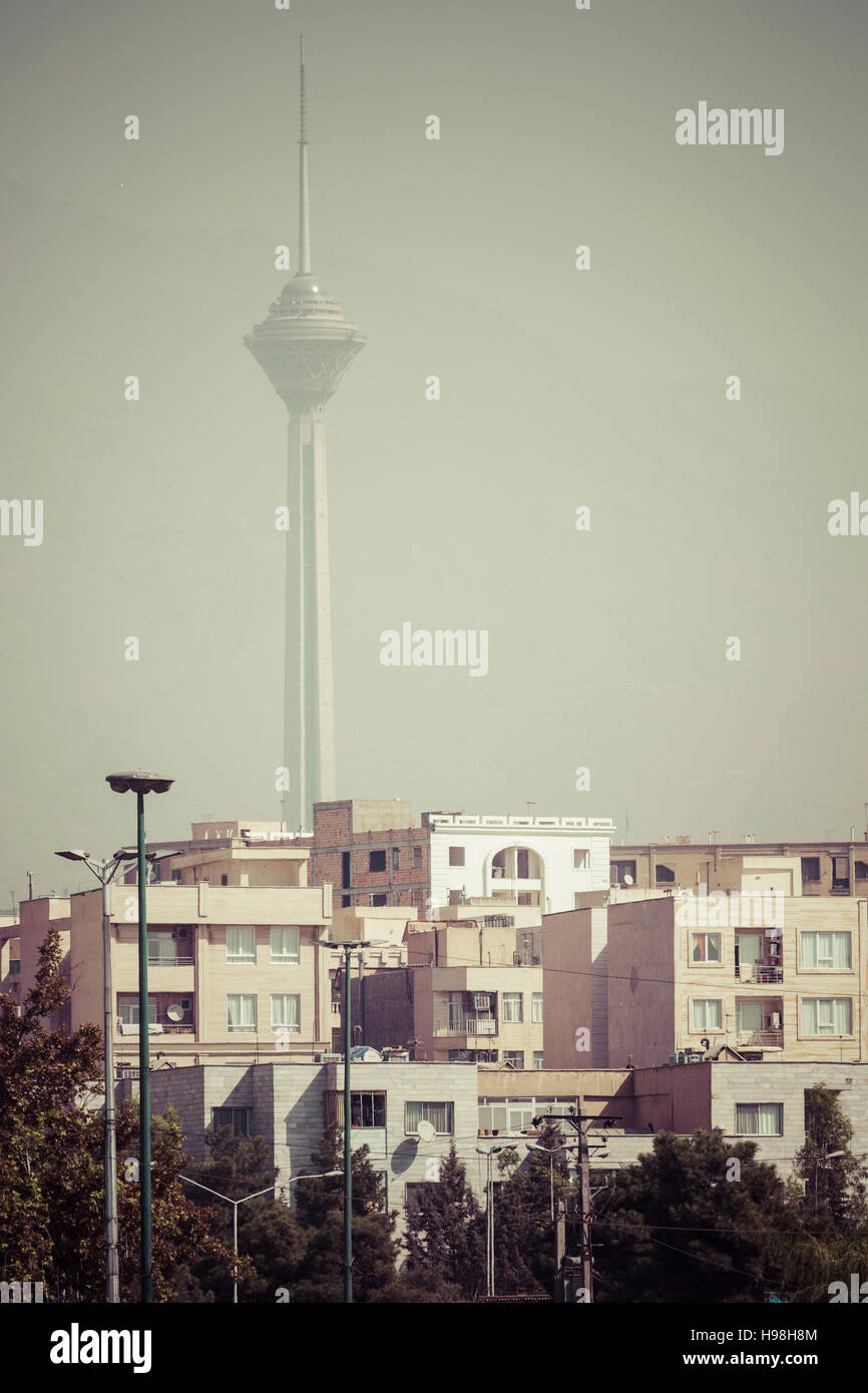 TEHERAN, IRAN - Ottobre 03, 2016: edifici residenziali a fronte di Milad Tower in aria contaminata skyline di Tehran illuminato con tramonto dorato. Foto Stock