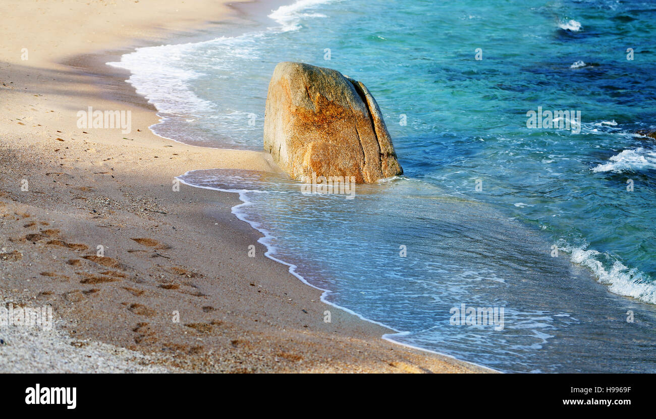 Bellissima spiaggia sul mare con una grossa pietra nella sabbia Foto Stock