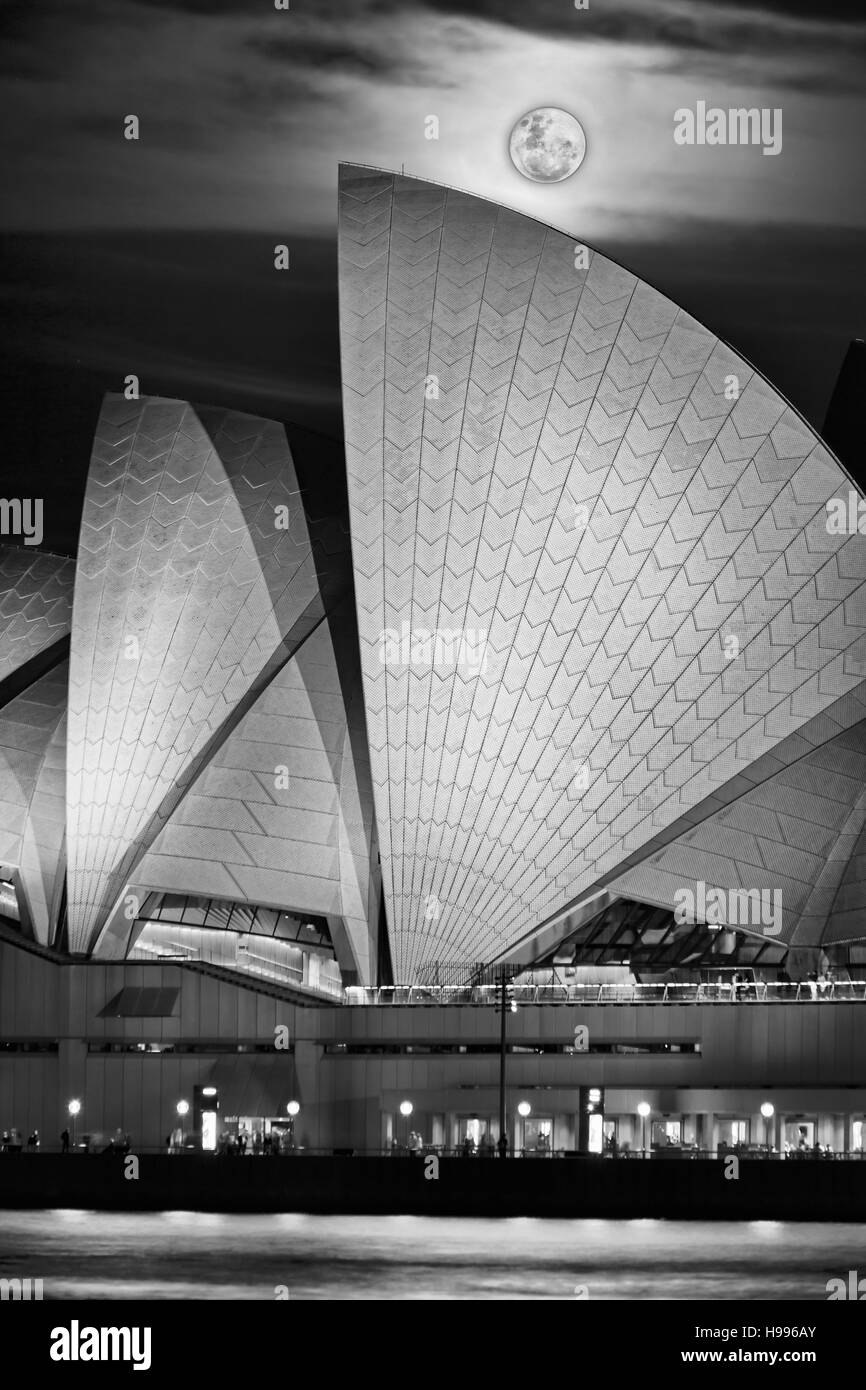 Verticale di bianco-nero in foto della piena rising super luna sopra Sydney punto di riferimento della città di Porto e di Circular Quay in una notte buia Foto Stock