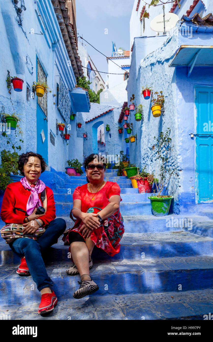 Due turisti cinesi posano per una fotografia in un colorato Street nella Medina, Chefchaouen, Marocco Foto Stock