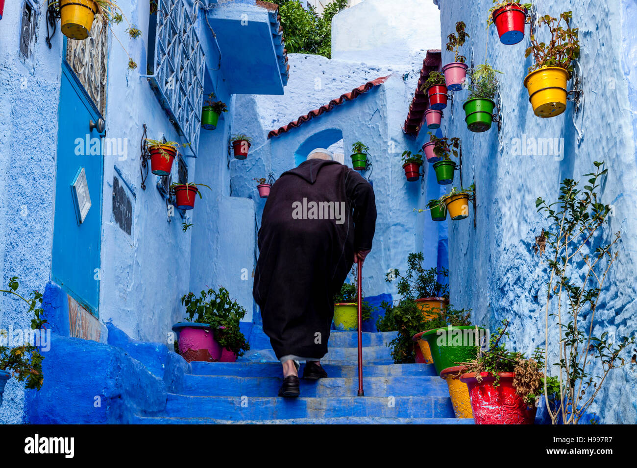 Un uomo anziano a camminare su una strada colorato nella Medina, Chefchaouen, Marocco Foto Stock