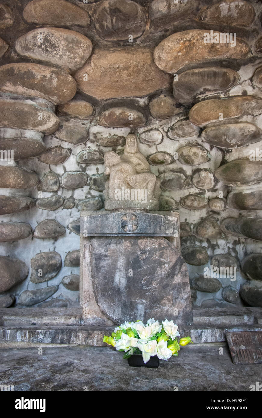 Statua di Pietà su altare di pietra con fiori alla Chiesa di Puh Sarang, un luogo di culto ben noto e meta turistica religiosa a Kediri, Indonesia. Foto Stock