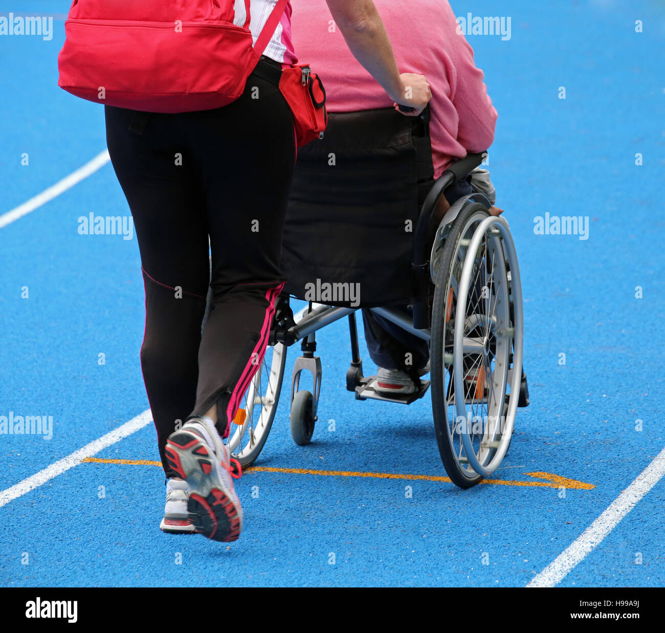 Sedia a rotelle di mobilità con un operatore sulla pista di atletica leggera durante l'evento sportivo Foto Stock