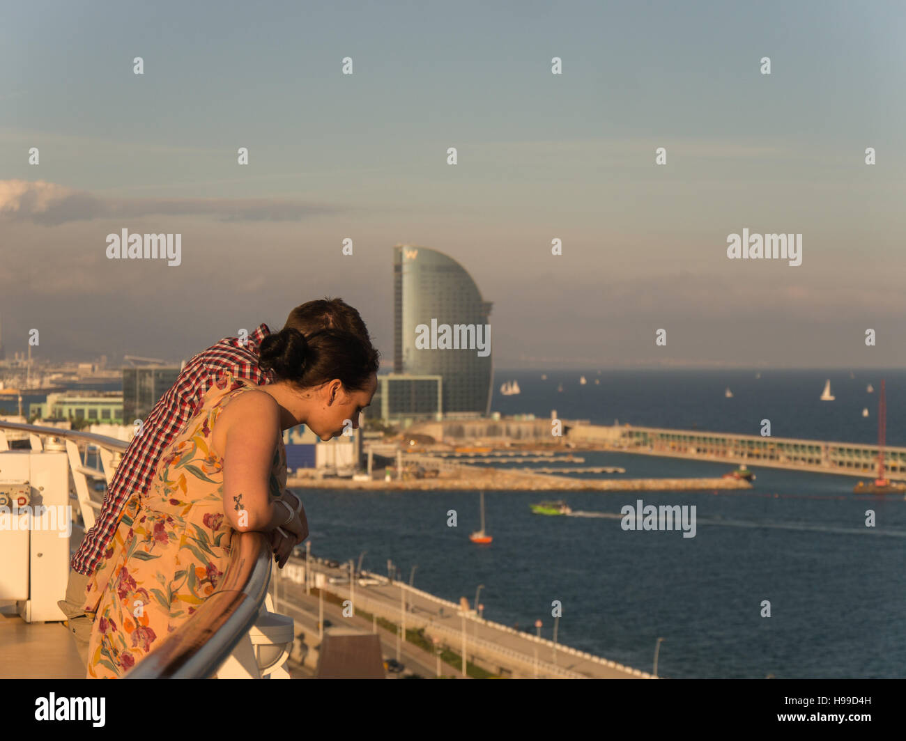 Un giovane appoggiata sopra la rotaia di Royal Caribbean armonia dei mari nave da crociera nel porto di Barcellona con il W Hotel nella parte posteriore Foto Stock