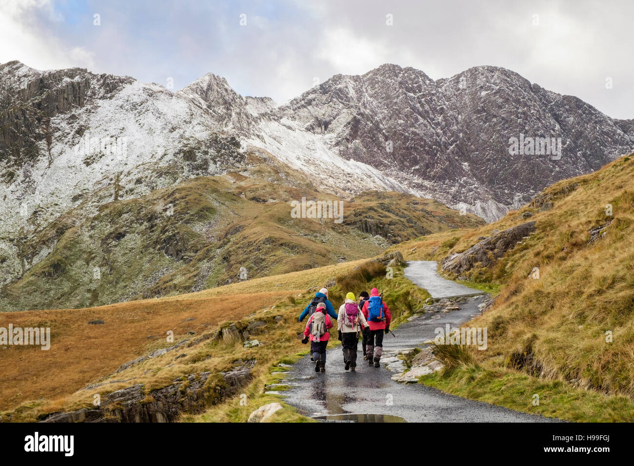 Gli escursionisti trekking sui minatori 'Via da Pen-y-Pass in Snowdon a ferro di cavallo con Y Lliwedd avanti e la neve in inverno. Parco Nazionale di Snowdonia (Eryri) Wales UK Foto Stock