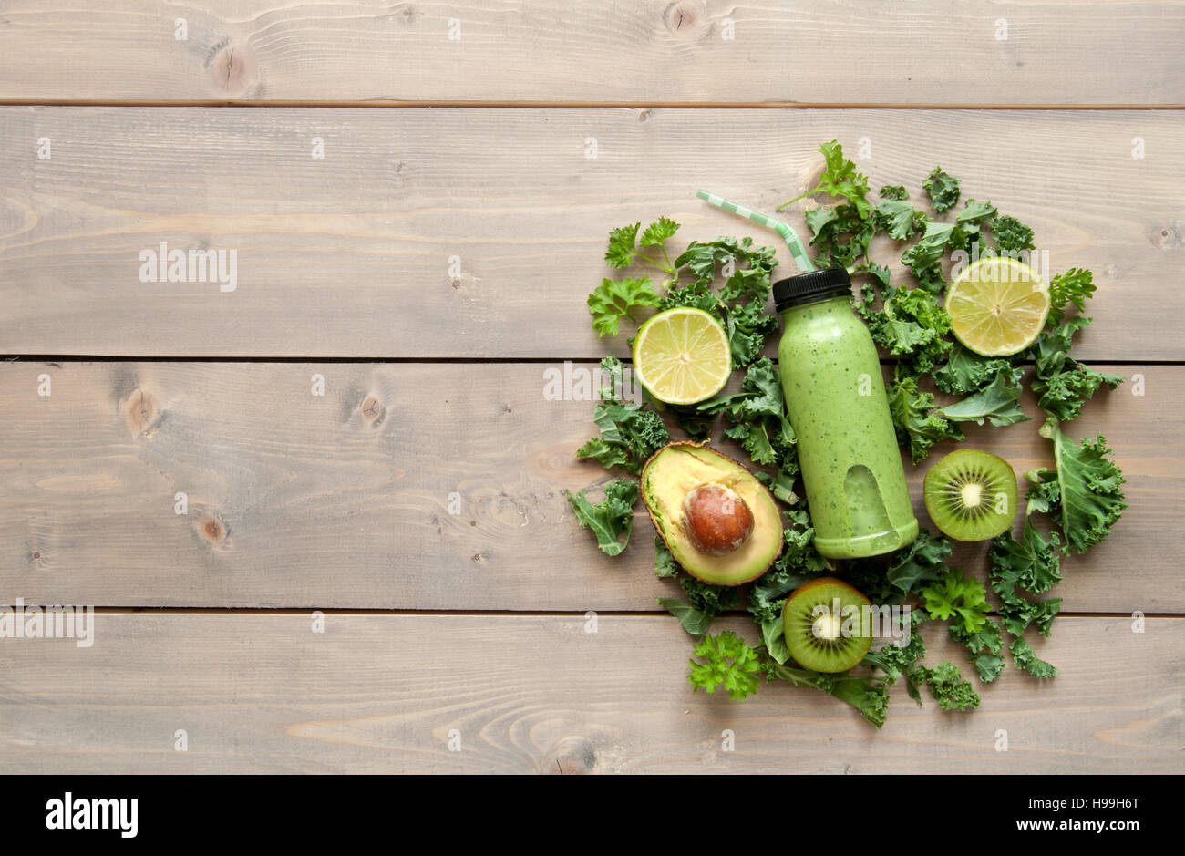 Frullato verde bevanda in una bottiglia al di sopra di un tavolo di legno con uno spazio Foto Stock