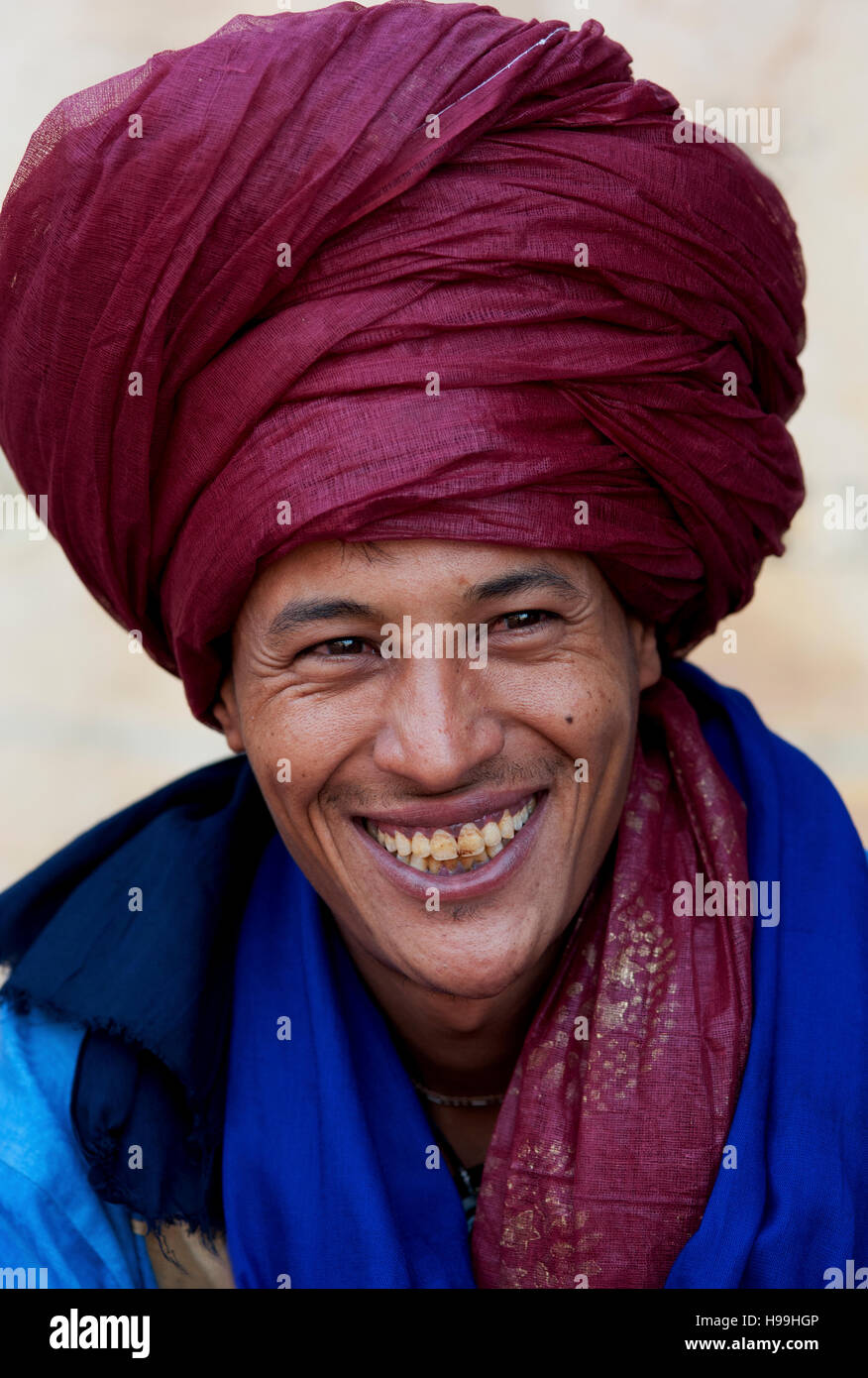 Ritratto di beduini nomadi con turbante rosso scarlatto e un grande sorriso vende la sua mercanzia in una popolare meta turistica Ait Benhaddou, Marocco. Foto Stock