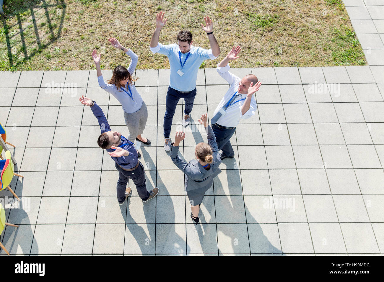 Un gruppo di uomini di affari che alzando le mani insieme in un cerchio Foto Stock