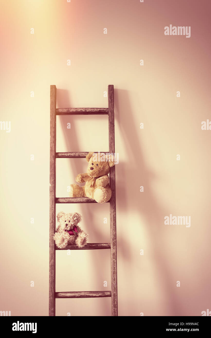 Due orsacchiotti seduto su una scala contro una parete Foto Stock