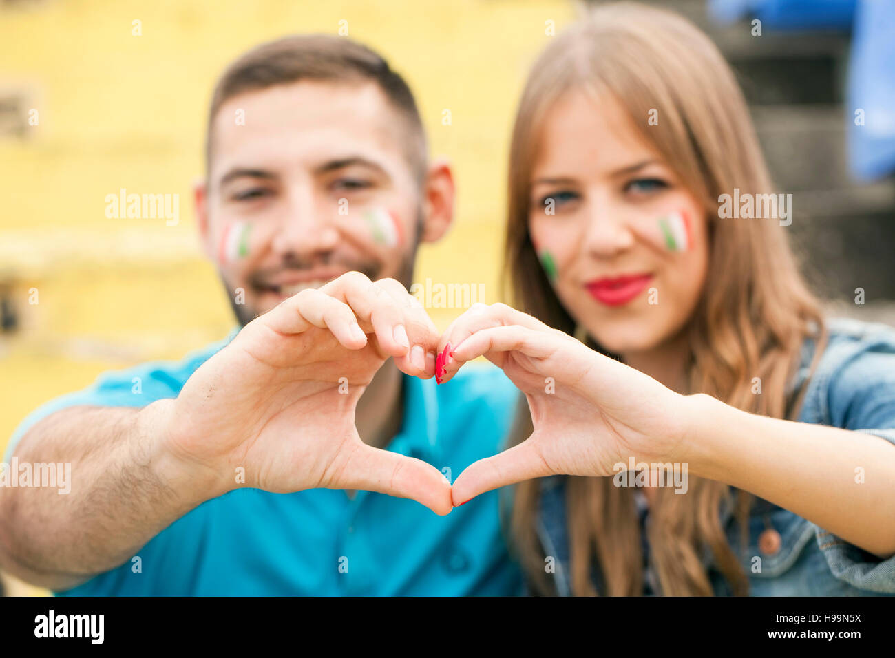 Coppia giovane con la faccia formante la vernice nel cuore con le mani Foto Stock