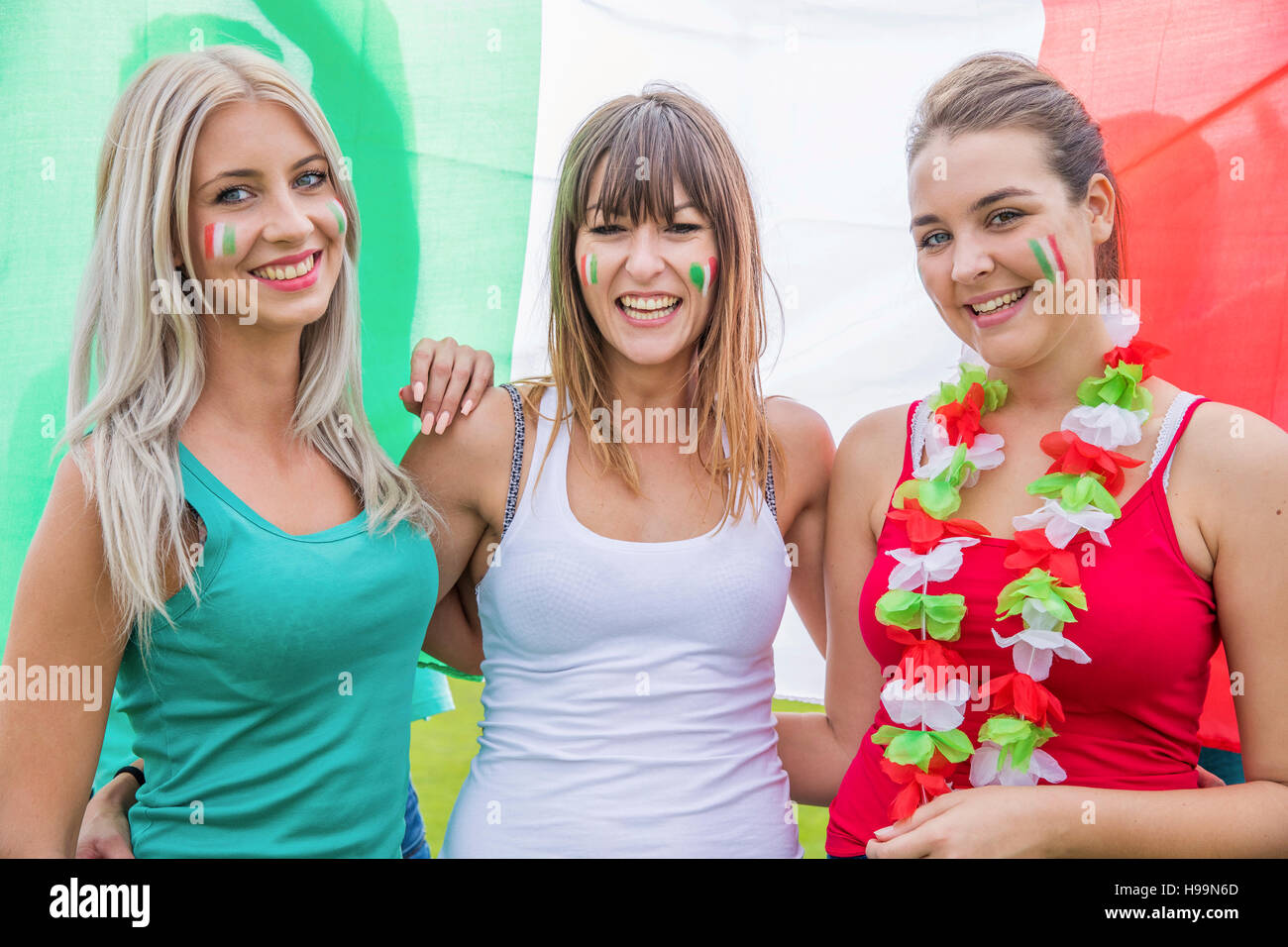 Tre donne appassionati di calcio in piedi con la bandiera italiana Foto Stock