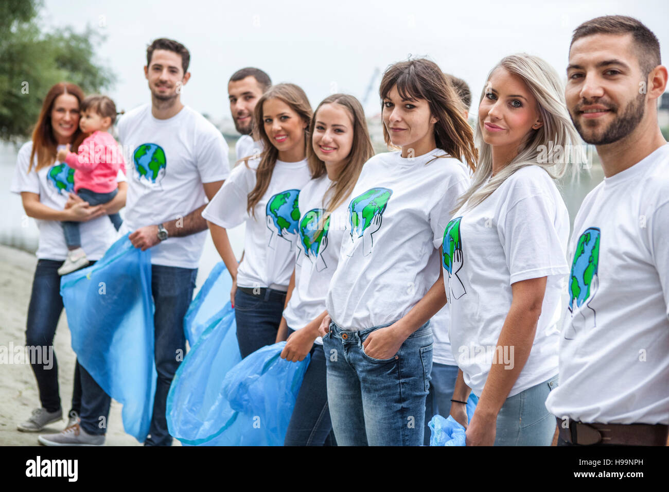 Volontari adolescenti facendo garbage pulizia riverbank Foto Stock
