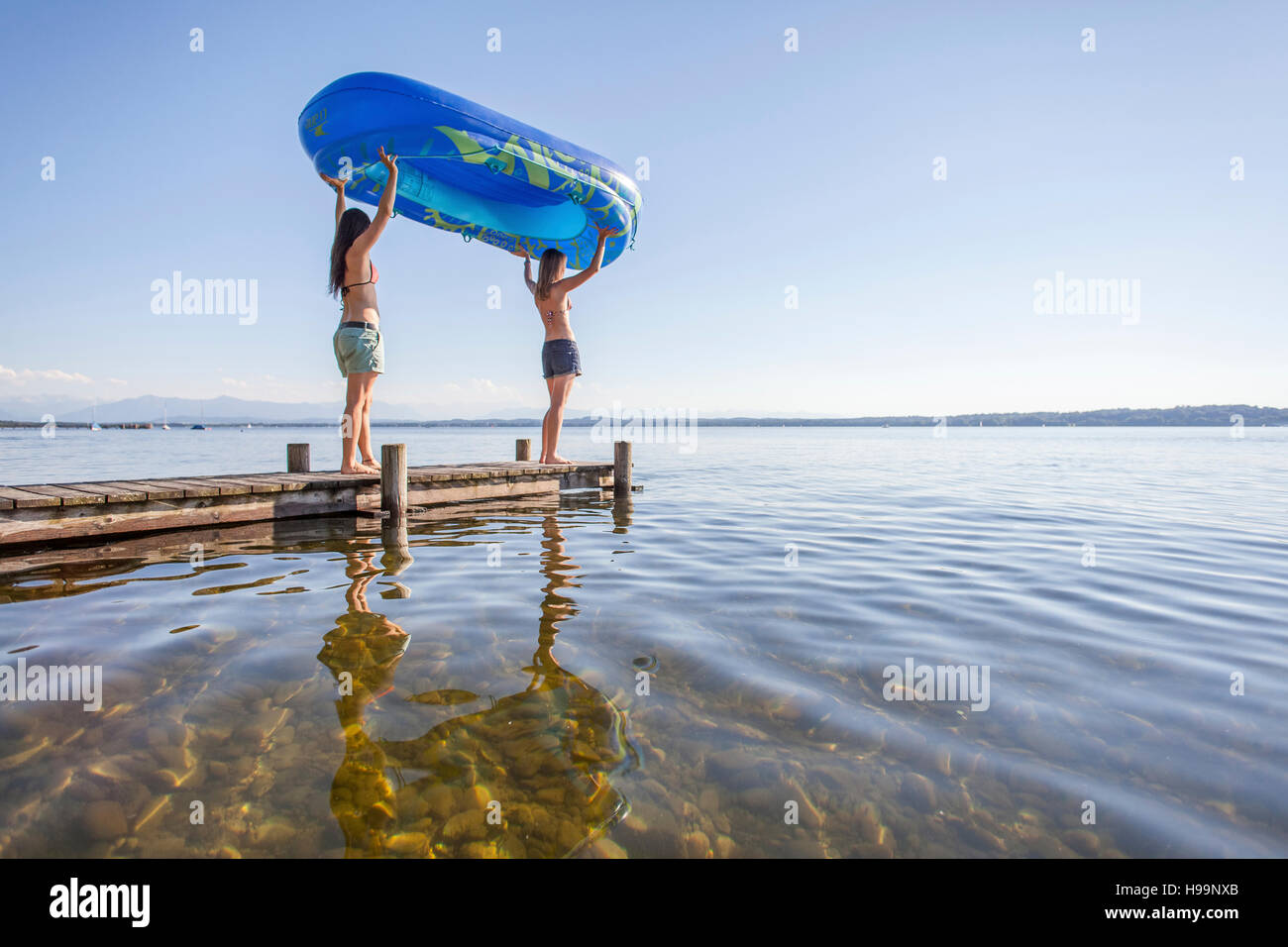 Due giovani donne che trasportano zattera gonfiabile sul Boardwalk Foto Stock
