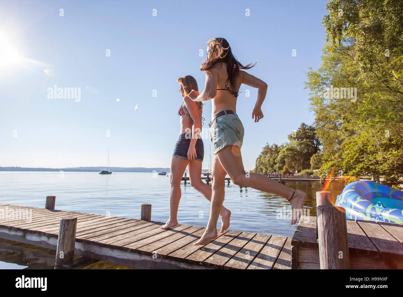 Due giovani donne in esecuzione sul molo sul lago di garda Foto Stock